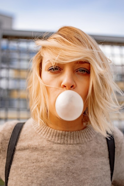 Stedelijk stijlvol jong meisje. Openlucht emotioneel portret van actief vrouwenmodel. Gezonde levensstijl. Mode-look, outdoor hipster portret. Sluit omhoog portret van een vrij jong meisje dat kauwgom kauwt.