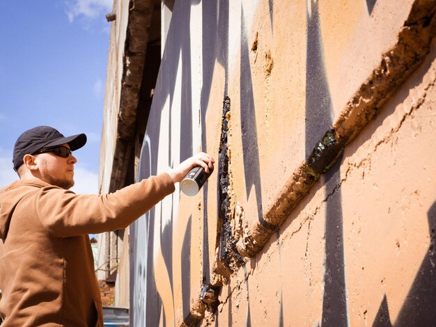 Stedelijke kunstenaar verf graffiti op de muur vandaal verf wilde stijl