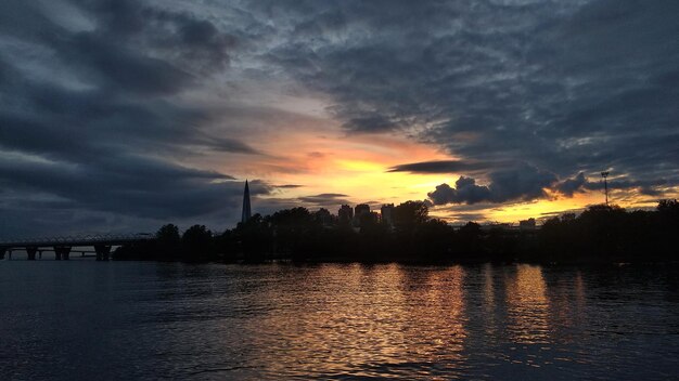Stedelijke landschappen. Kleurrijke zonsondergang en nacht uitzicht op de dijk, rivier en wolkenkrabber gebouw. S