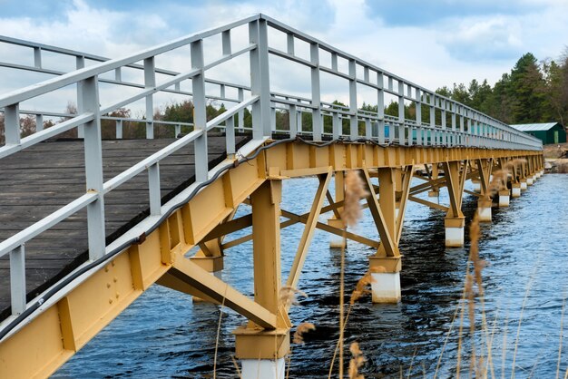 Steel bridge along river bank, blue sky at background