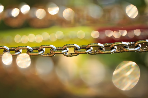 Steel chain with selective focus on a green natural background with bright bokeh beautiful concept b...