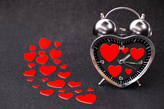 Стальной будильник в виде сердца с красными сердцами внутри на черном блестящем блестящем фоне С Днем Святого Валентина