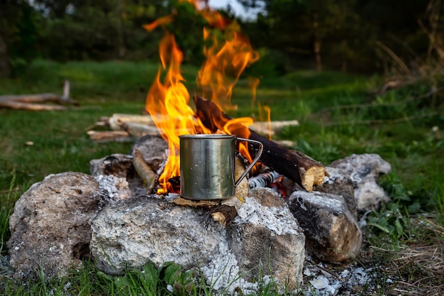 Steel cup on an open fire in nature Cooking on fire Camping in summer