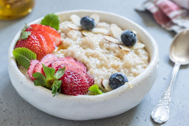 Steel cut oatmeal porridge with strawberry blueberry and honey for breakfast