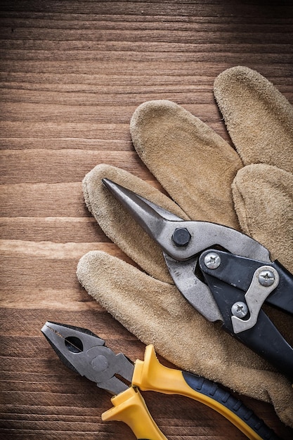 Steel cutter pliers leather protective gloves on wooden board