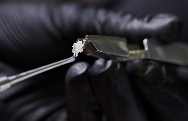 Photo steel dental forceps with ceramic bracket and a hand with a tiny colorful brush