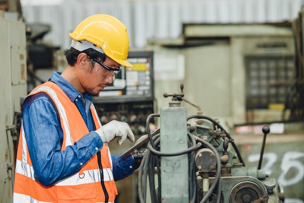 철강 공장 직원 아시아 남자는 안전 엔지니어 유니폼을 입은 중공업 기계에서 일합니다.