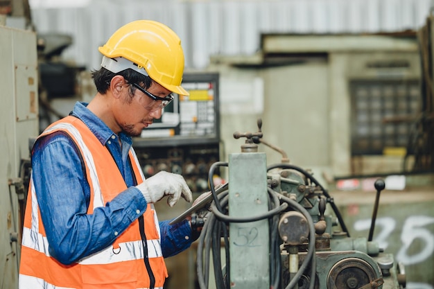 Photo steel factory staff worker asian man work in a heavy industrial machine with safety engineer uniform