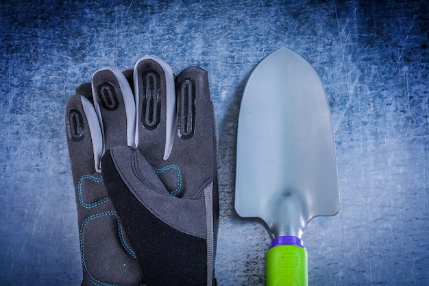 Steel gardening shovel fabric gloves on metallic surface agriculture concept.