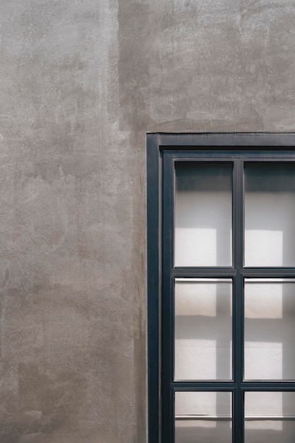 Steel and glass window on concrete loft wall of vintage house with sunlight and shadow on surface