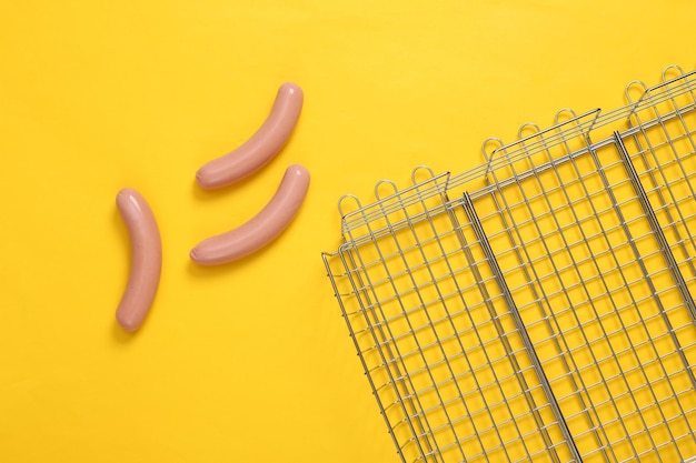 Steel grid for grill with sausages on yellow background