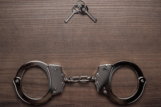 Steel handcuffs and keys on the wooden background