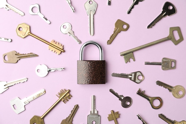 Steel padlock and keys on pink background flat lay Safety concept