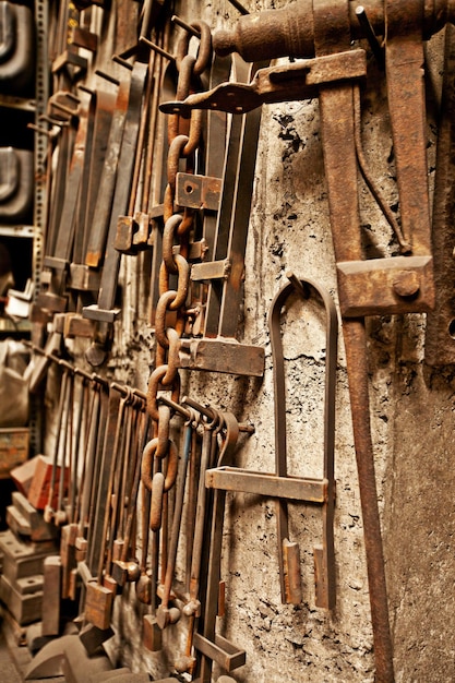 鍛冶屋の職場と産業工場の壁の背景に鋼鉄のツールとワークショップ、製造倉庫や真鍮鍛造産業機器を吊り下げるための職人のレトロな金属ツール