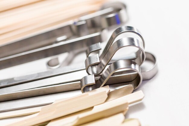 Steel and wood skewers on a white painted wood background.