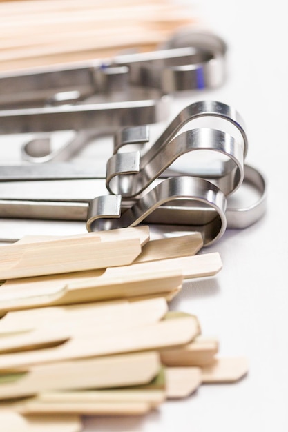 Steel and wood skewers on a white painted wood background.