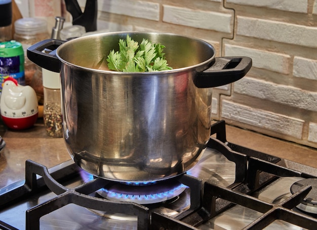 Steelpan op gasfornuis met peterselieschotel die wordt voorbereid