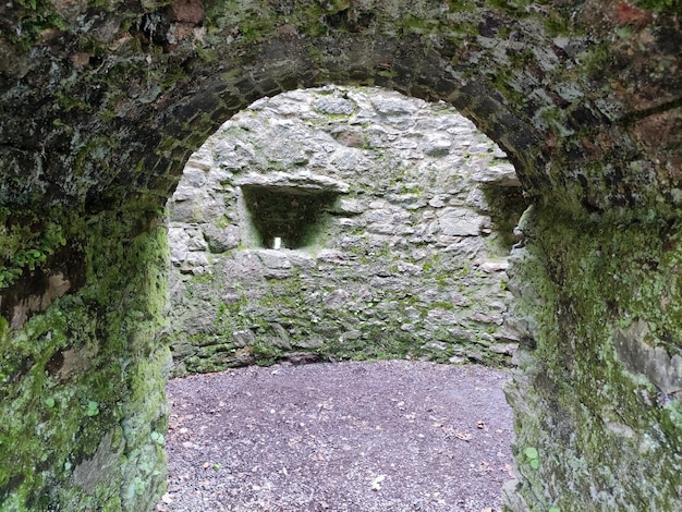 Steenboog van oude Keltische vesting een Blarney-kasteel in de rotsen en bergenachtergrond van Ierland