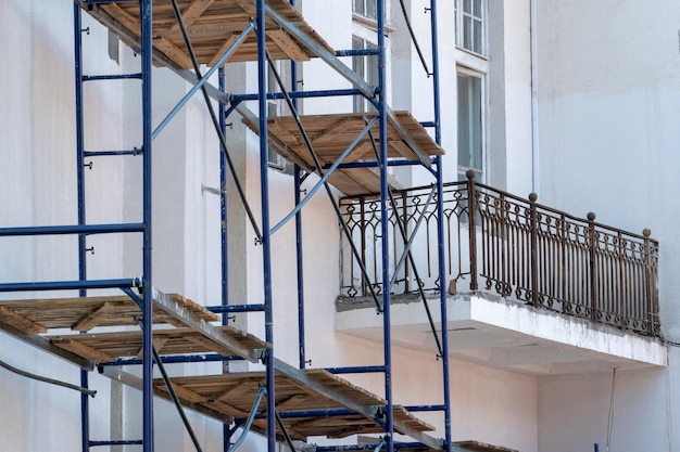 Steiger gemaakt van metalen profiel en houten vlonder langs het gebouw tijdens de renovatie Restauratie van een oud gebouw in het historische centrum van de stad Reparatie van het dak en de gevel