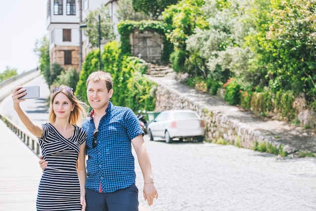 Stel man en vrouw die door de stad lopen en samen romantische en gelukkige selfies maken