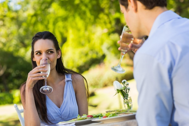 Stel met champagnefluiten samen die bij een openluchtcafÃ © zitten