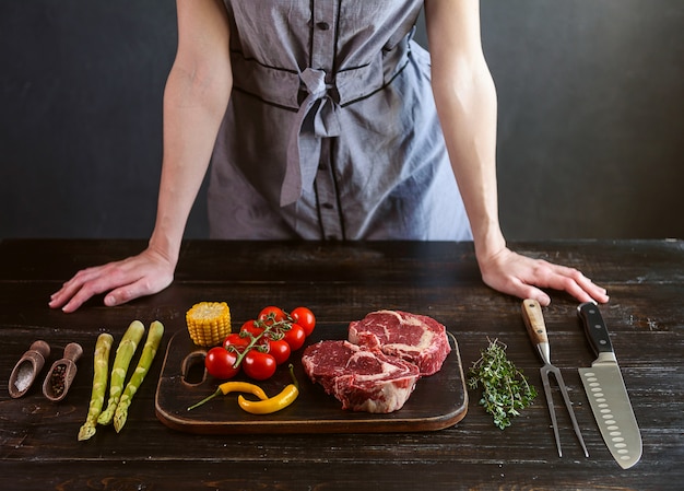 Stel voor het koken van een feestelijk diner voor twee. twee rauwe gemarineerde biefstuk, kruiden, groenten