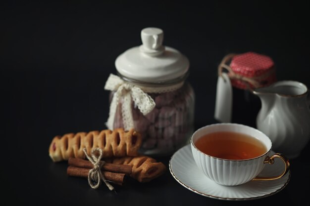 Stel voor het ontbijt. Snoep en gebak met noten voor thee op zwarte achtergrond. Een kopje koffie en pasteitjes.