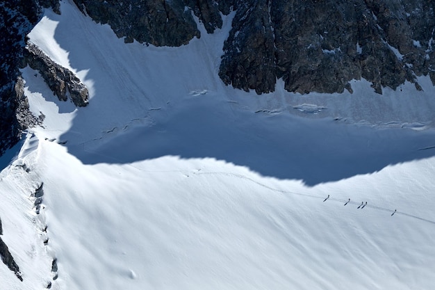 Stelletje bergbeklimmers klimt of alpinisten naar de top van een besneeuwde berg op gletsjer