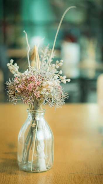 Stelletje gedroogde bloemen in een glazen vaas op houten tafel