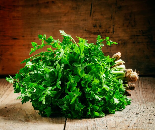 Stelletje groene platte blad Italiaanse peterselie in rieten mand op een oude houten tafel selectieve focus