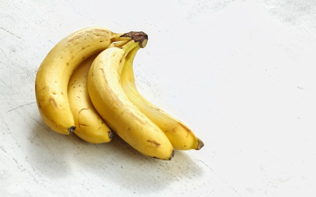 Stelletje rijpe bananen op witte werkbord.