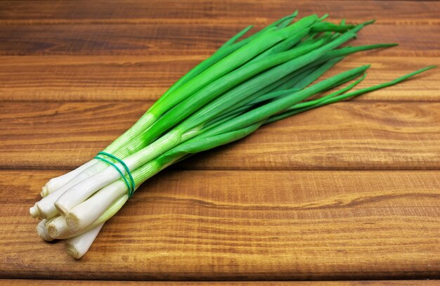 Stelletje verse groene uien op een houten tafel. Verse groene ui op houten achtergrond