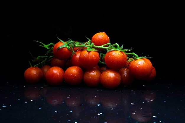 Stelletje verse, rode tomaten met groene stengels cherrytomaatjes op donkere achtergrond