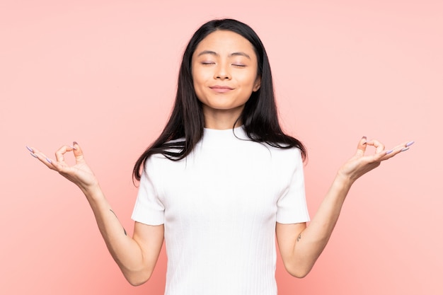 Stelt de tiener Chinese vrouw op roze muur in zen