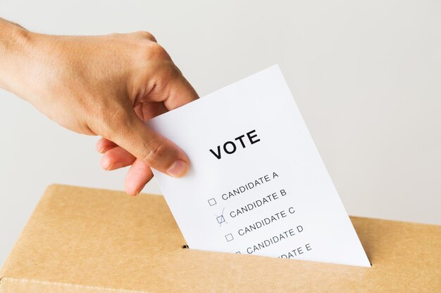 Foto stemmen, burgerrechten en mensenconcept - close-up van mannenhand die bij verkiezingen stemmen in de stembus stopt