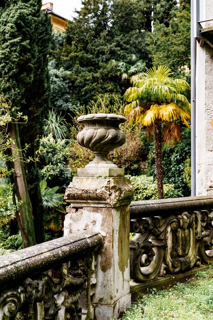 Stenen balustrade met een vaas tegen een achtergrond van palmen en cipressen villa monastero italië