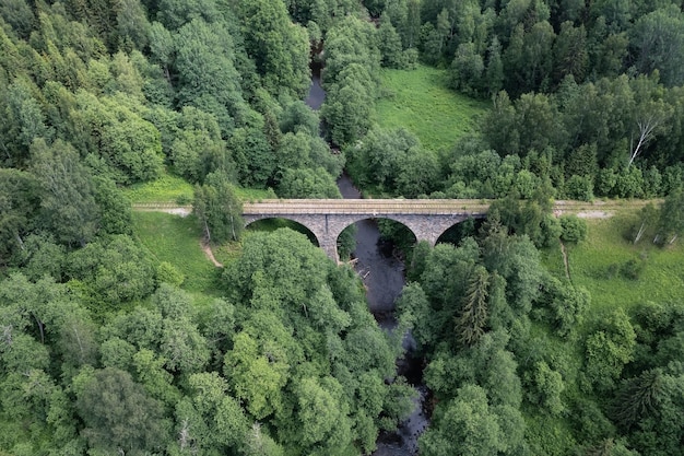Stenen brug over riviertje op verlaten gedeelte van oude spoorweg begroeid met gras en bomen