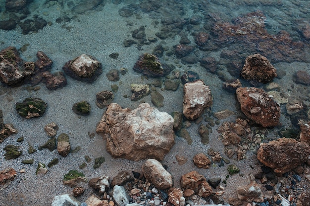 Stenen liggend op het zand omringd door de Middellandse Zee