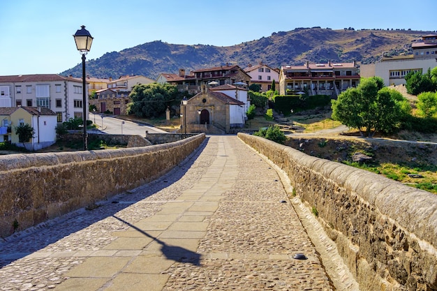Stenen pad over een middeleeuwse Romaanse brug naar de oude huizen van de Barco de Avila Spanje