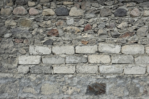 Stenen van verschillende afmetingen en vormen liggen op elkaar. cement tussen hen. T