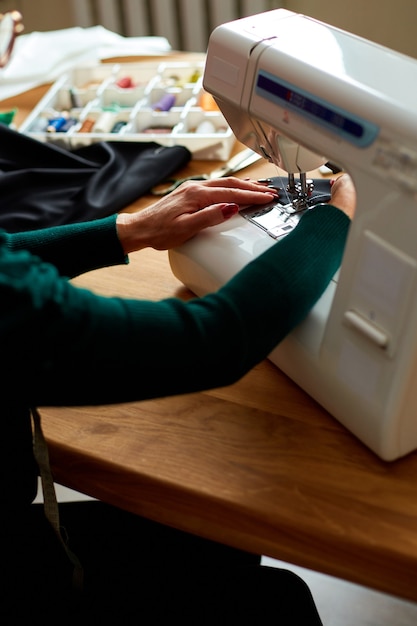 Step by step, 50-yers old woman sews clothes on sewing machine, Mature tailor working with sewing in atelier, textile industry, hobby, workspace.