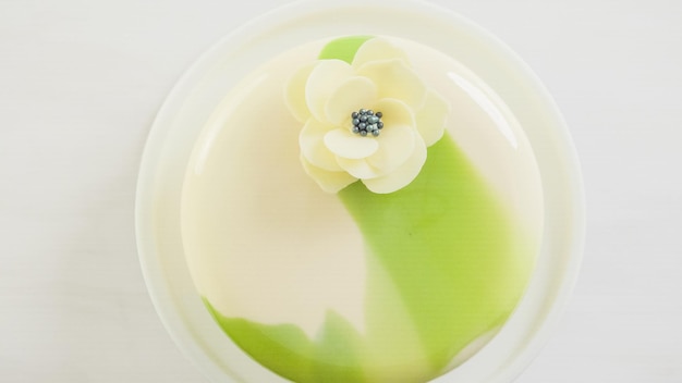 Step by step. Baking gourmet mousse cake with white and green mirror glaze decorated with white chocolate flower.