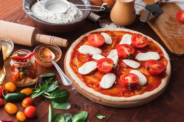 Il capo passo dopo passo prepara una pizza margarita. ingredienti per impasto e pizza