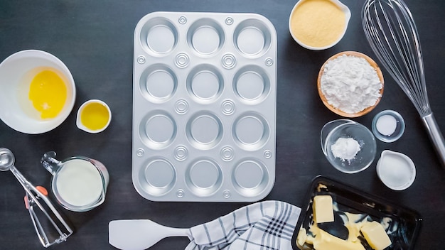 Step by step. Buttering metal cupcake pan to bake cornbread muffins.