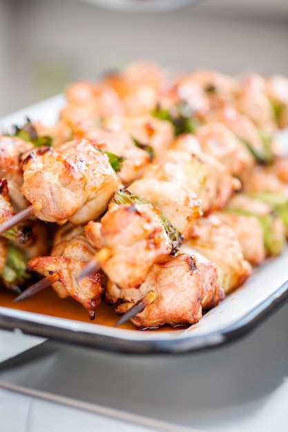 Step by step. Chicken yakitori with scallions on white metal serving tray.