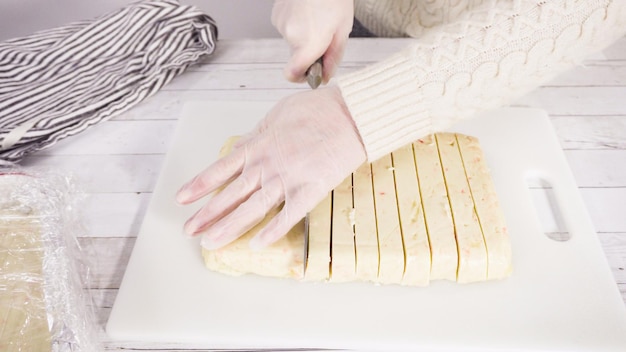 Step by step. Cutting homemade candy cane fudge on a white cutting board.