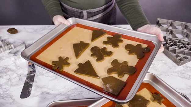 Step by step. Cutting out shapes with Christmas cookies cutter from gingerbread cookie dough.