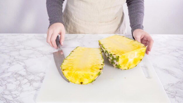 Step by step. Cutting pineapple on a white cutting board.