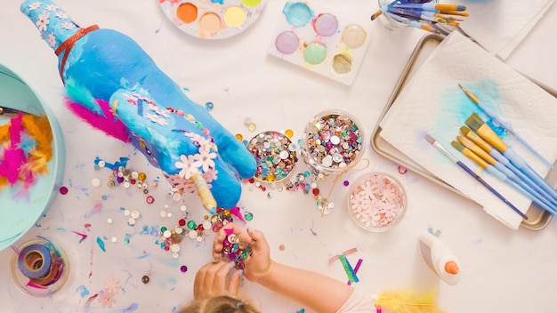 Step by step. Decorating painted paper mache unicorn with paper flowers and jewels.