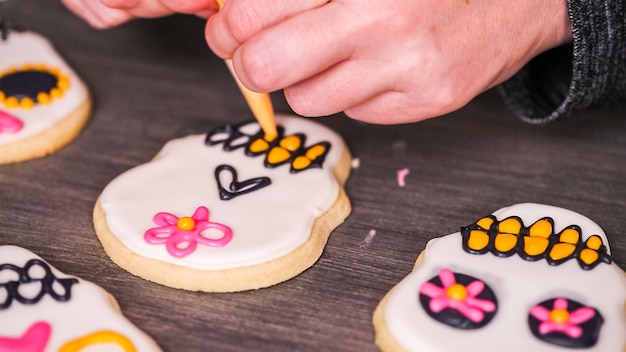 Step by step. Decorating sugar skull cookies with different color royal icing.